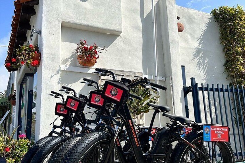 A white building with a red sign, a black bicycle, and a blue sign. 2