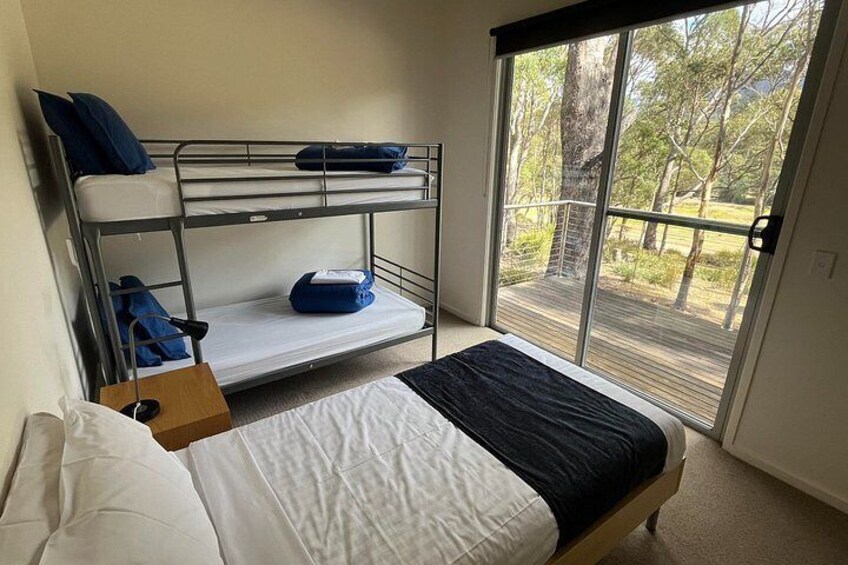 A bunk bed, a single bed, and a sliding glass door leading to an outdoor area. 2