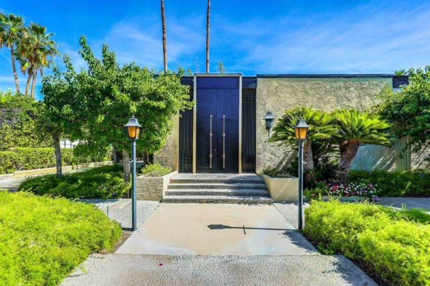 A modern building with a dark entrance, surrounded by lush greenery and palm trees. 5