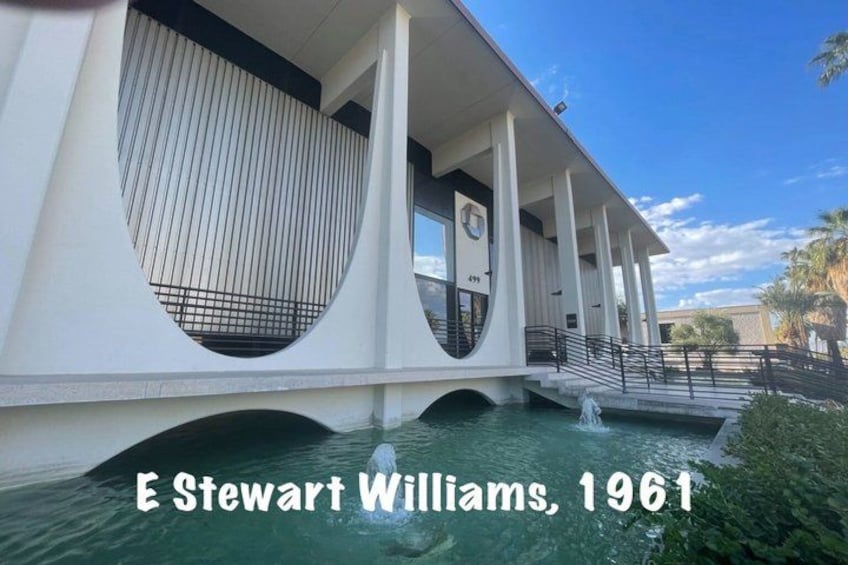 A modern building with a unique architectural design, featuring large circular windows and a bridge over a body of water. 3