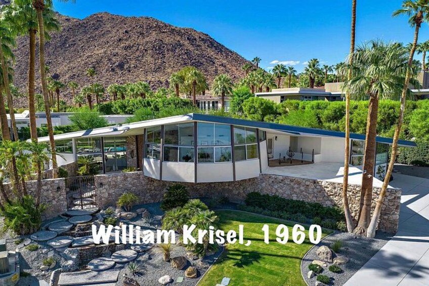 A modern house with a stone foundation, surrounded by palm trees and a mountain in the background. 5