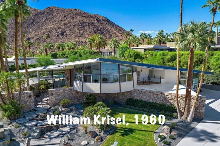 A modern house with a stone foundation, surrounded by palm trees and a mountain backdrop. 5
