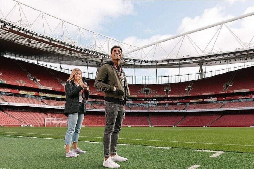 A stadium with empty stands, a person standing on the field, and another person taking a photo. 5
