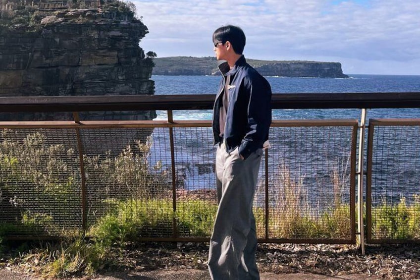 A person standing by a railing overlooking a coastal cliff and ocean. 2