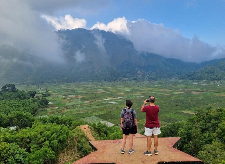 Two people standing on a platform overlooking a terraced landscape with a mountain in the background. 5