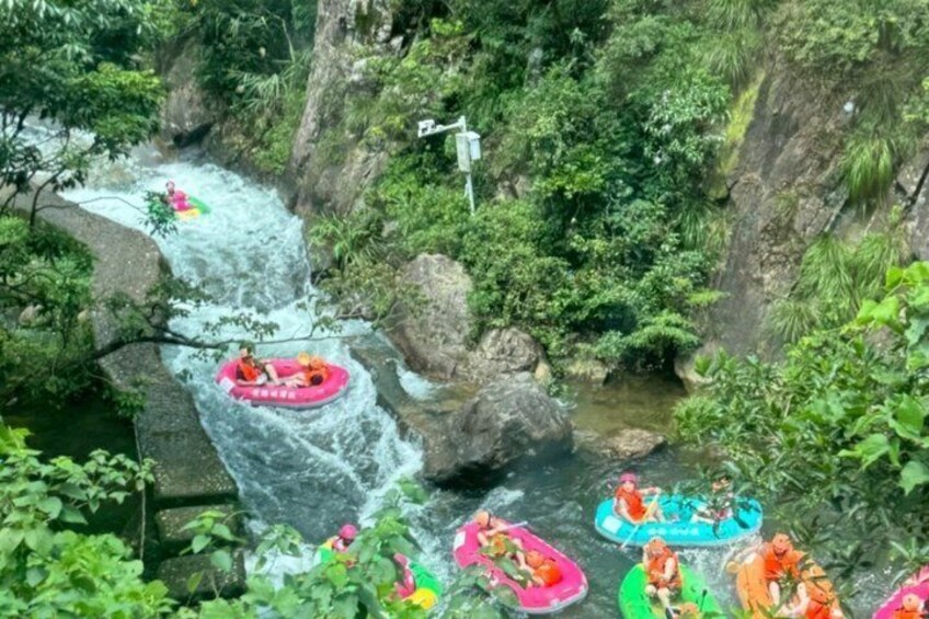 People rafting down a river with rapids, surrounded by lush greenery and rocky terrain. 4