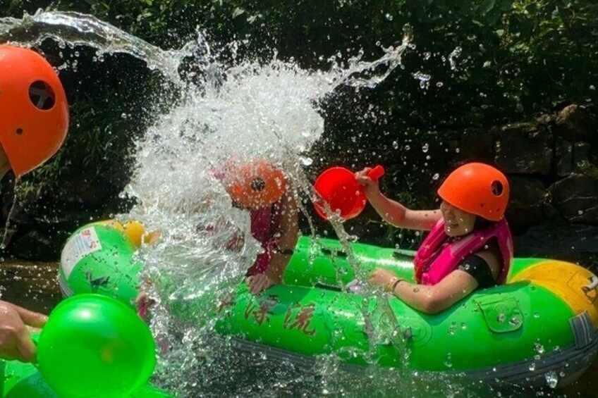 A person in a green raft with a helmet, splashing water. 5