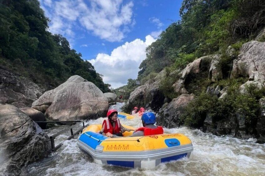 A river rafting activity with participants in a yellow raft navigating through a rocky riverbed. 1