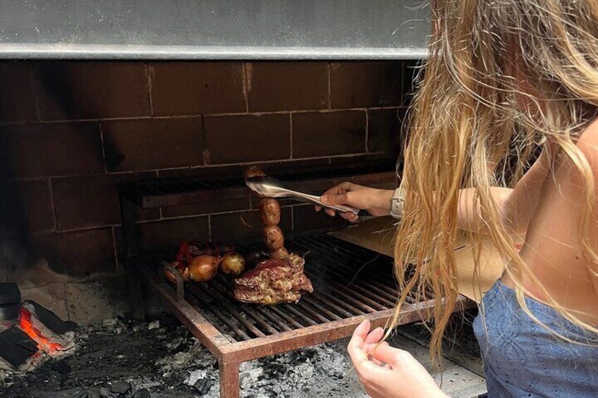 A person grilling meat on an outdoor grill with a brick oven in the background. 2