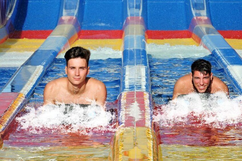 Two people sliding in a water slide with colorful lanes. 5