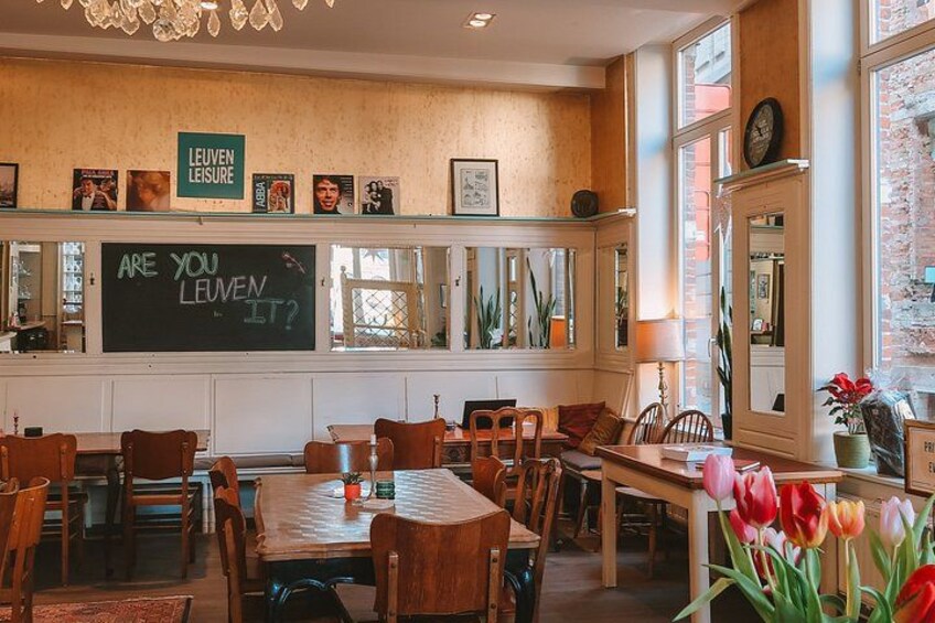 A cozy cafe interior with wooden furniture, a chalkboard sign, and a brick wall. 4