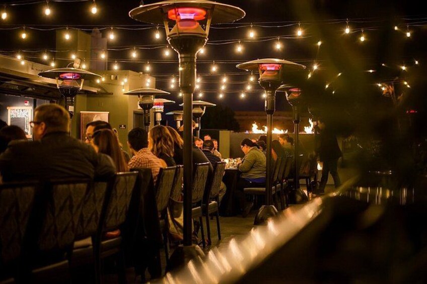 An indoor dining area with tables and chairs, overhead string lights, and a warm ambiance. 4