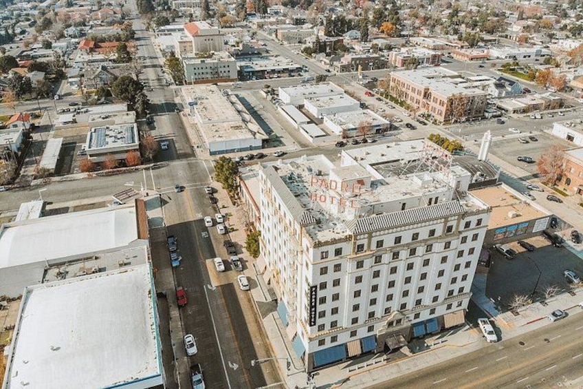An aerial view of a cityscape with a prominent building labeled 'PADRE HOTEL' and a large parking lot. 2