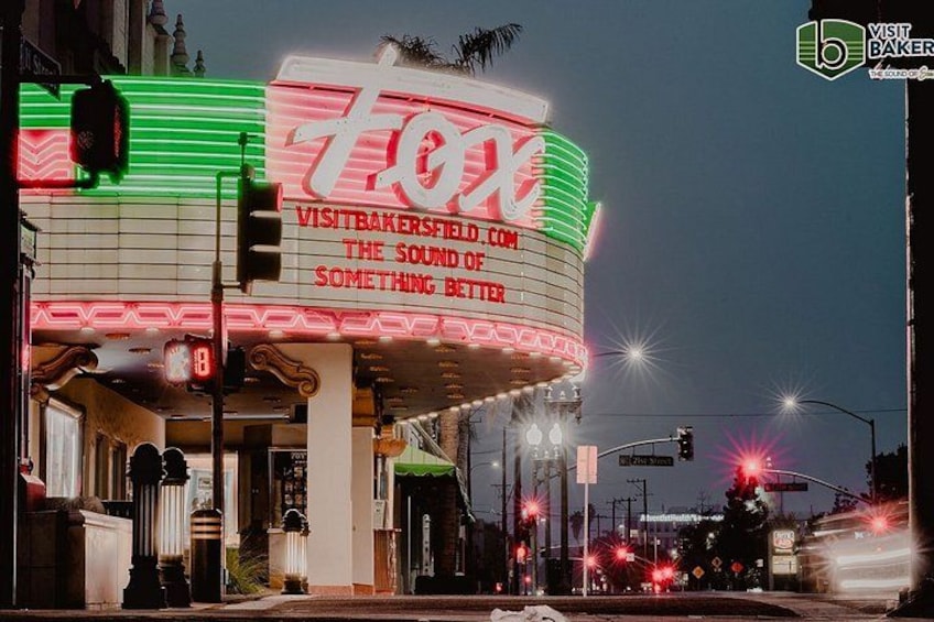 A neon-lit theater marquee with the number 700X and a website address. 1