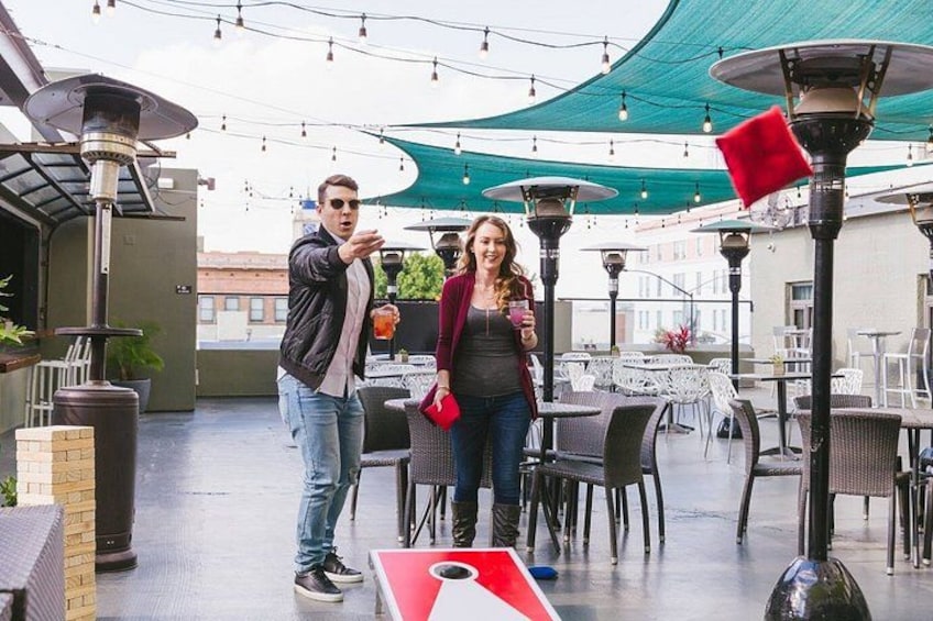 An outdoor patio with tables and chairs, a person holding a drink, and another person gesturing. 3