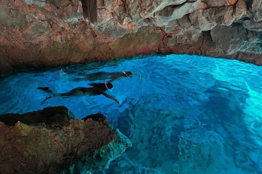 A person swimming in a clear blue pool with rocky walls. 2