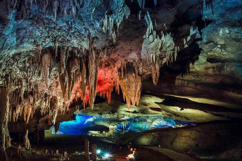 A cave with stalactites and stalagmites, illuminated by colored lights. 2