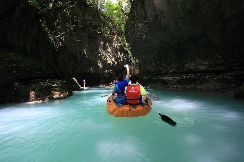 A person in a raft navigating a calm river surrounded by rocky cliffs. 3