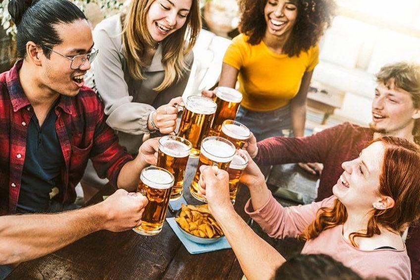 A group of people toasting with beer mugs at a table. 1