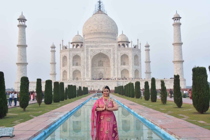 A person in traditional attire standing in front of the Taj Mahal. 3