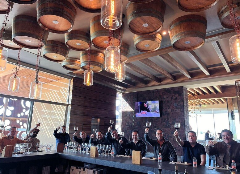 A bar with wooden barrel chandeliers and a group of people toasting with wine glasses. 2