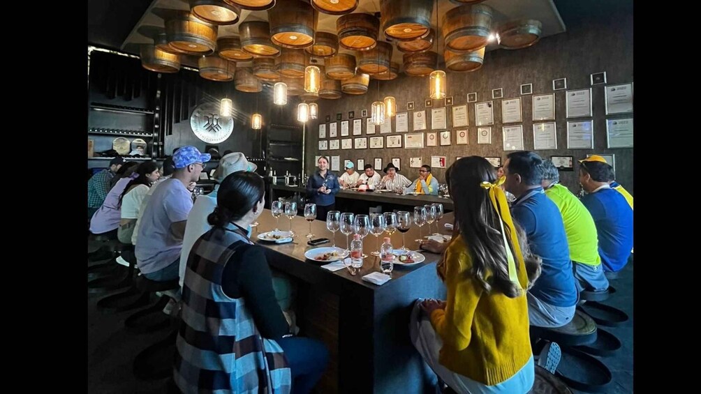A bar with wooden barrel lighting, a bartender, and patrons seated at tables. 1