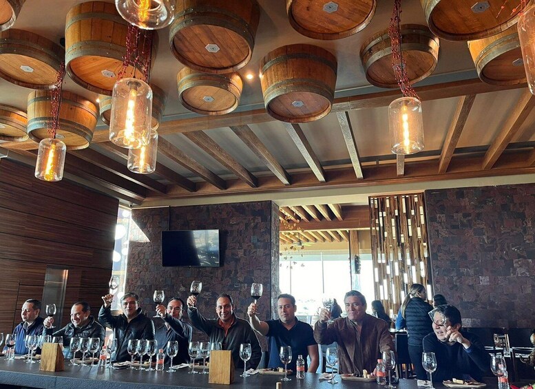 A group of people toasting with wine glasses at a bar with wooden barrels as ceiling decor. 5