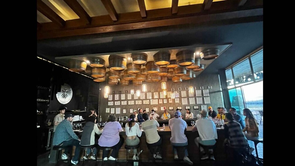 A group of people seated at a bar with a wall of certificates and awards. 3