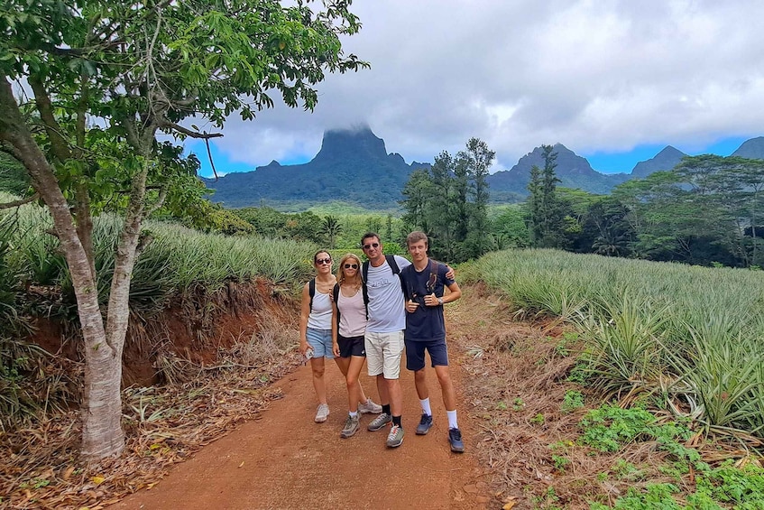 A group of people standing on a dirt path surrounded by lush greenery and mountains in the background. 2