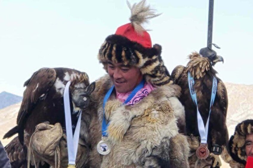 A person in traditional attire with a fur coat and a red hat, carrying a bird on their back. 2