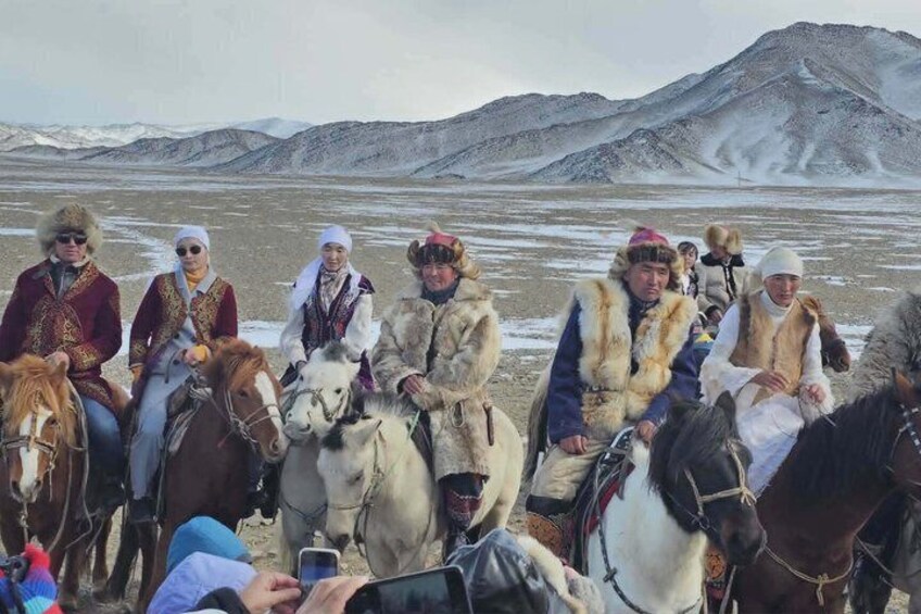 A group of people on horseback in a barren landscape with mountains in the background. 3