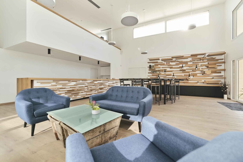 A modern interior with blue armchairs, a glass coffee table, and a wooden wall panel. 3