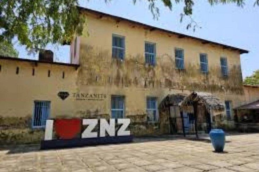 A building with a sign that reads 'TANZAMITES' and a logo with 'NZ' on a paved area. 2