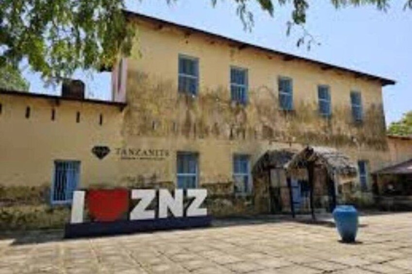A building with a sign reading 'TANZANIA' and 'I-ZNZ' in front. 2