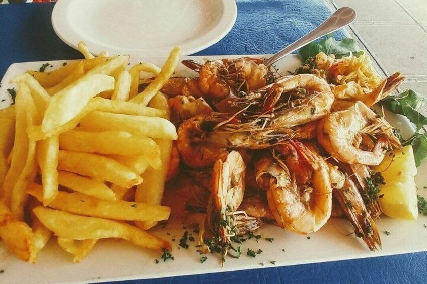 A plate of shrimp and fries with a small bowl of sauce. 3