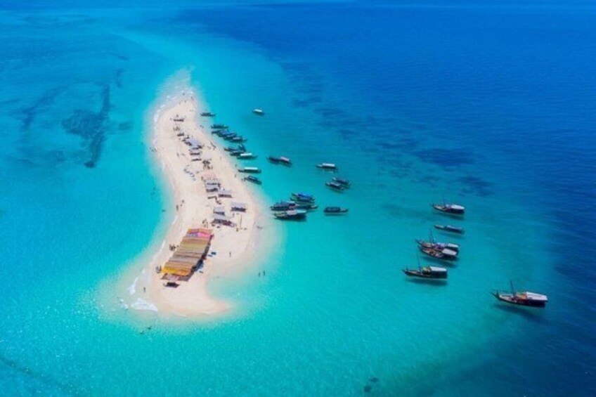 An aerial view of a beach with boats and a row of beach huts. 1