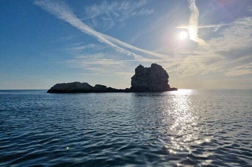A calm sea with a rocky outcrop and a clear sky. 5