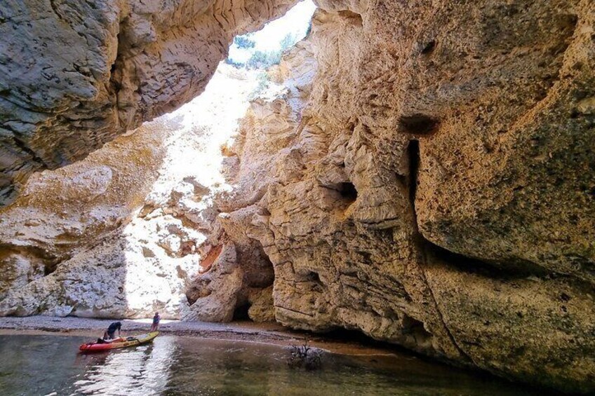 A person kayaking in a narrow canyon with rocky walls and a small stream. 2