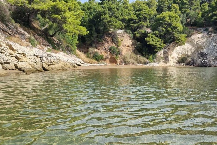 A calm lake with clear water, surrounded by rocky cliffs and dense green trees. 3