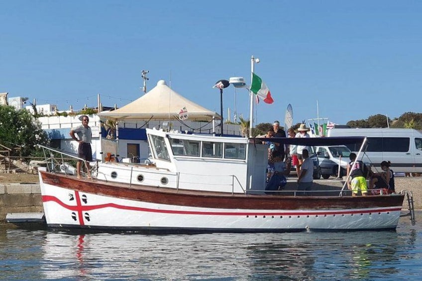 A boat with people on board, docked near a building with a flag. 2