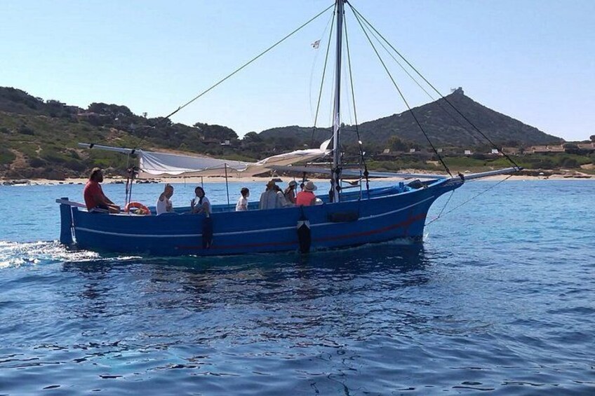A blue boat with people on it, a sandy beach, and a hill in the background. 4