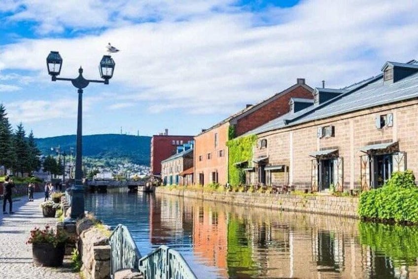 A canal with buildings on one side, a lamp post, and a clear sky. 2