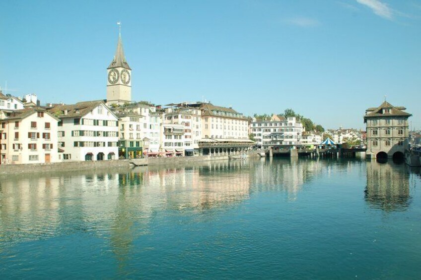 A river with buildings and a clock tower reflecting in the water. 1