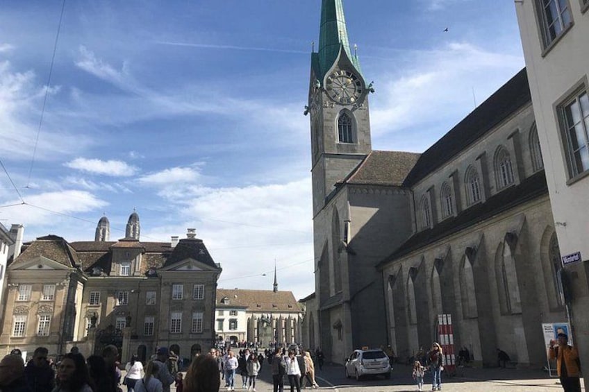 A historic building with a clock tower, a crowd of people, and a clear sky. 3