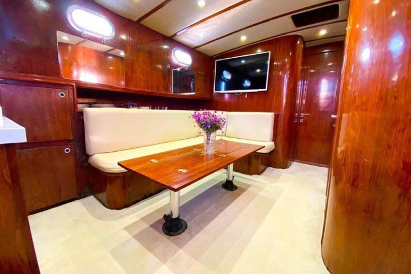 A wooden interior with a bench, a table with a vase, and a mounted television. 3