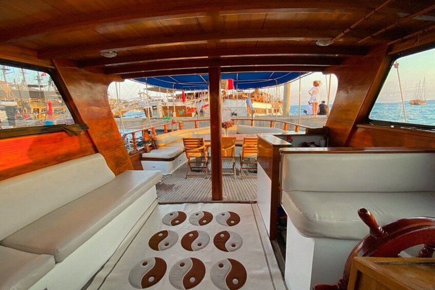 A boat deck with seating, a steering wheel, and a view of the marina. 5