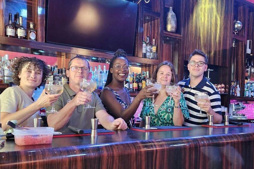 A group of people at a bar with bottles and glasses. 5