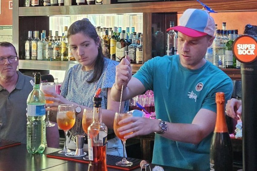 A bartender preparing drinks at a bar with various bottles and glasses. 4