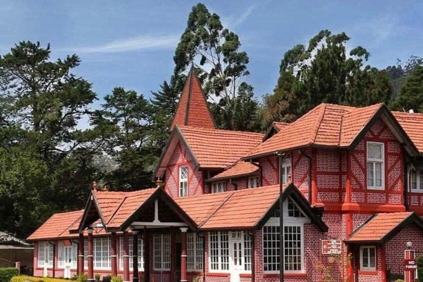 A red brick building with multiple gabled roofs and a prominent tower. 4