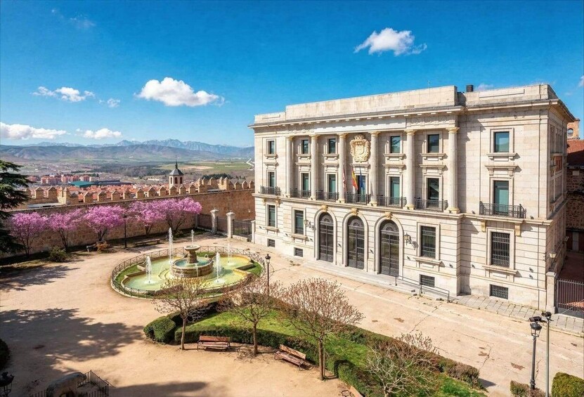 A historic building with a courtyard, a fountain, and blooming trees. 4